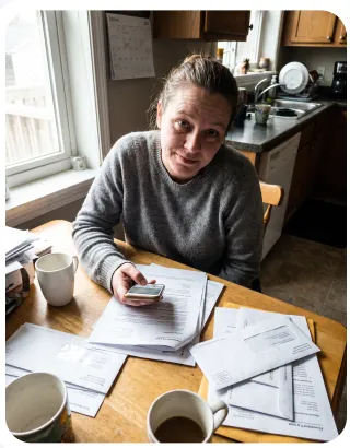 A kitchen table covered in paper receipts being photographed